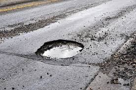 Large water-filled pothole on a cracked asphalt road